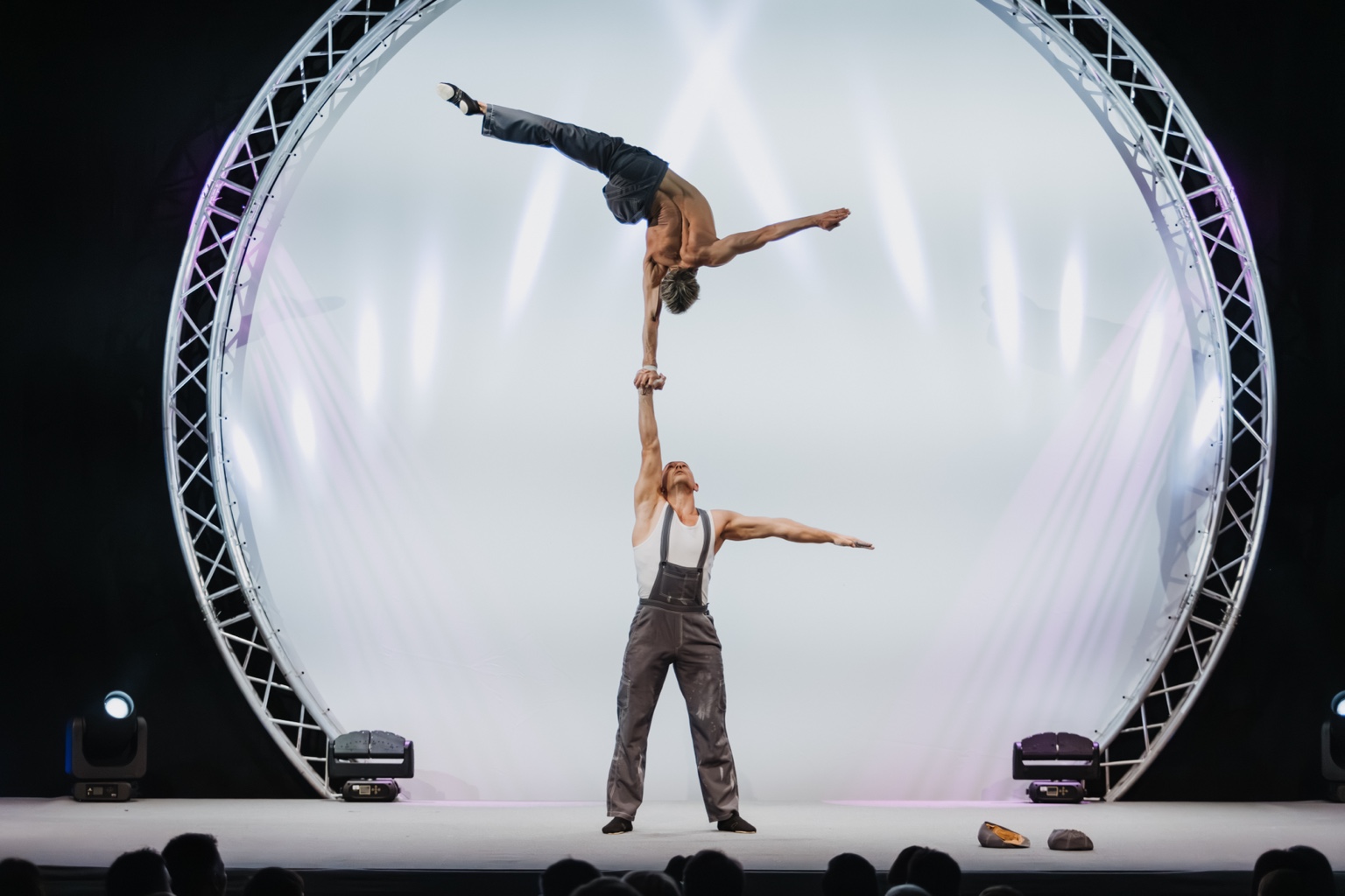 One-arm hand-to-hand balance inside a circular stage frame