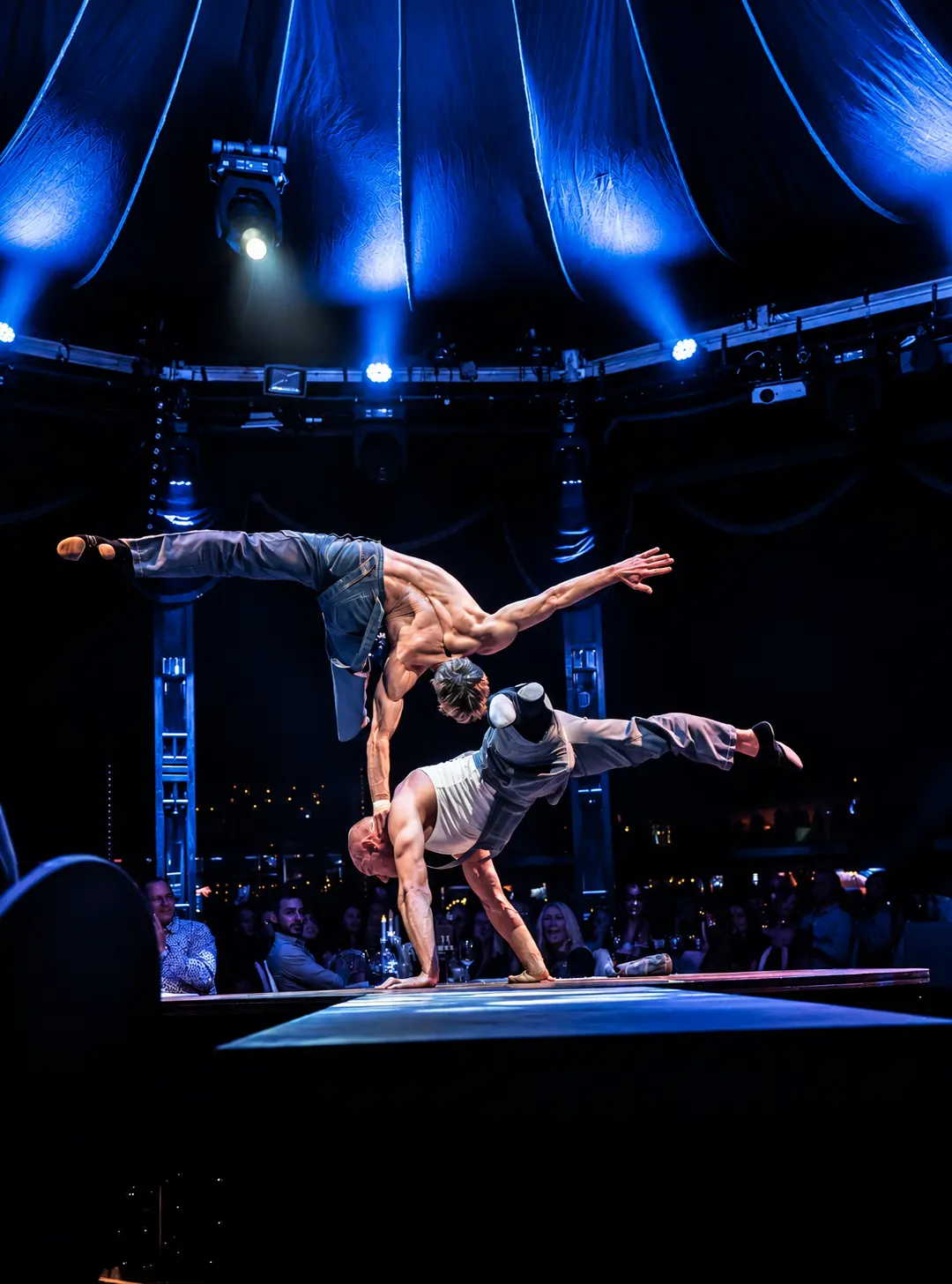 Double balance under dramatic blue circus lighting